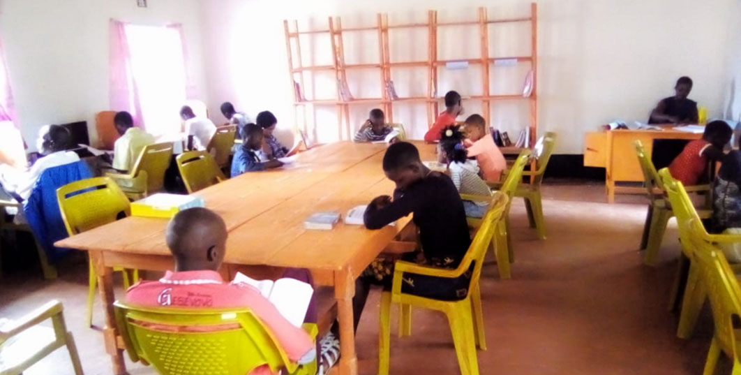 Children in Kenya reading books at tables.